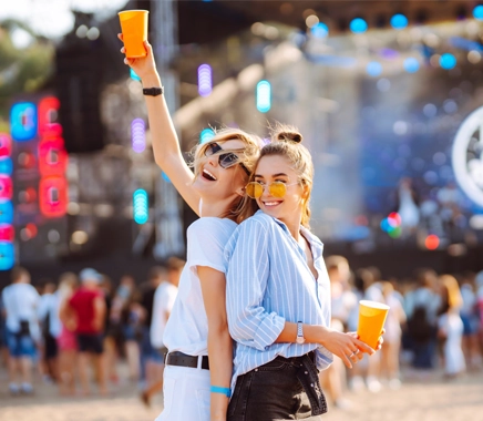 Twee jonge vrouwen staan in de zon te dansen op een festival