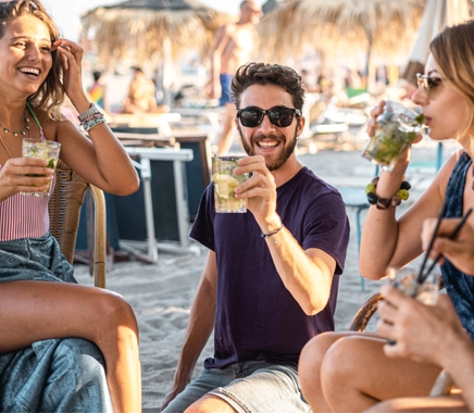 Groep mensen geniet op het strand met een cocktail en lachen met elkaar