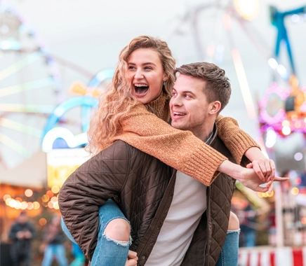 Kong koppel verliefd genieten van tijd op de kermis met achtbaan op achtergrond